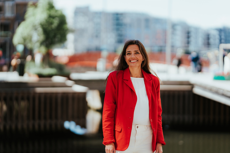 Kvinne i rød blazer smiler til kamera.