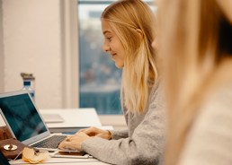 ung blond kvinne som sitter å skriver på en bærbar PC