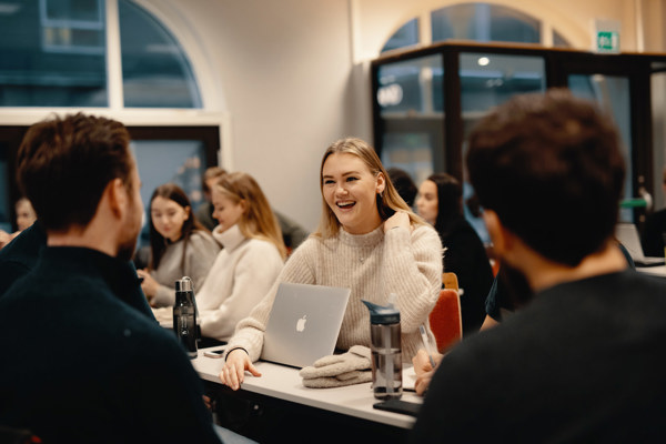 Bilde av ung kvinne som smiler til medstudenter.