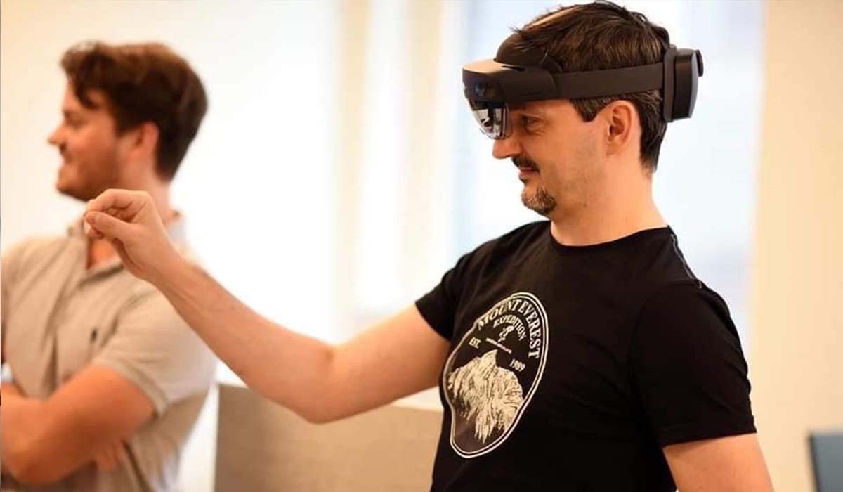 En mann prøver på smartbriller mens han holder hånden opp foran ansiktet.