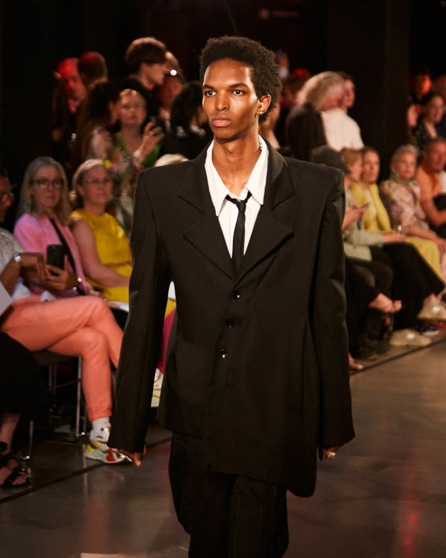 Mannlig modell viser frem klær på en catwalk. 