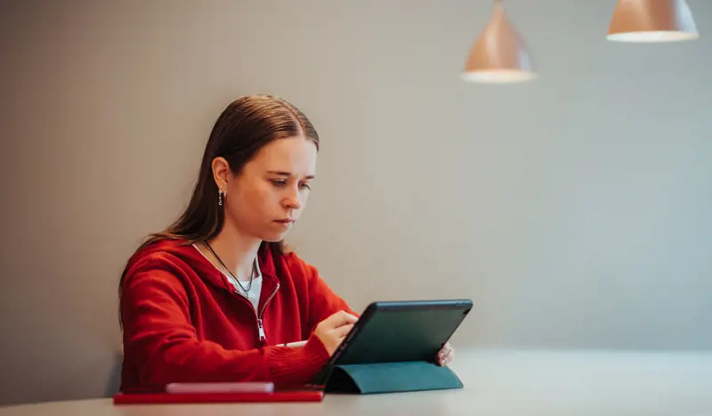 Kvinne i rød genser jobber på en tablet