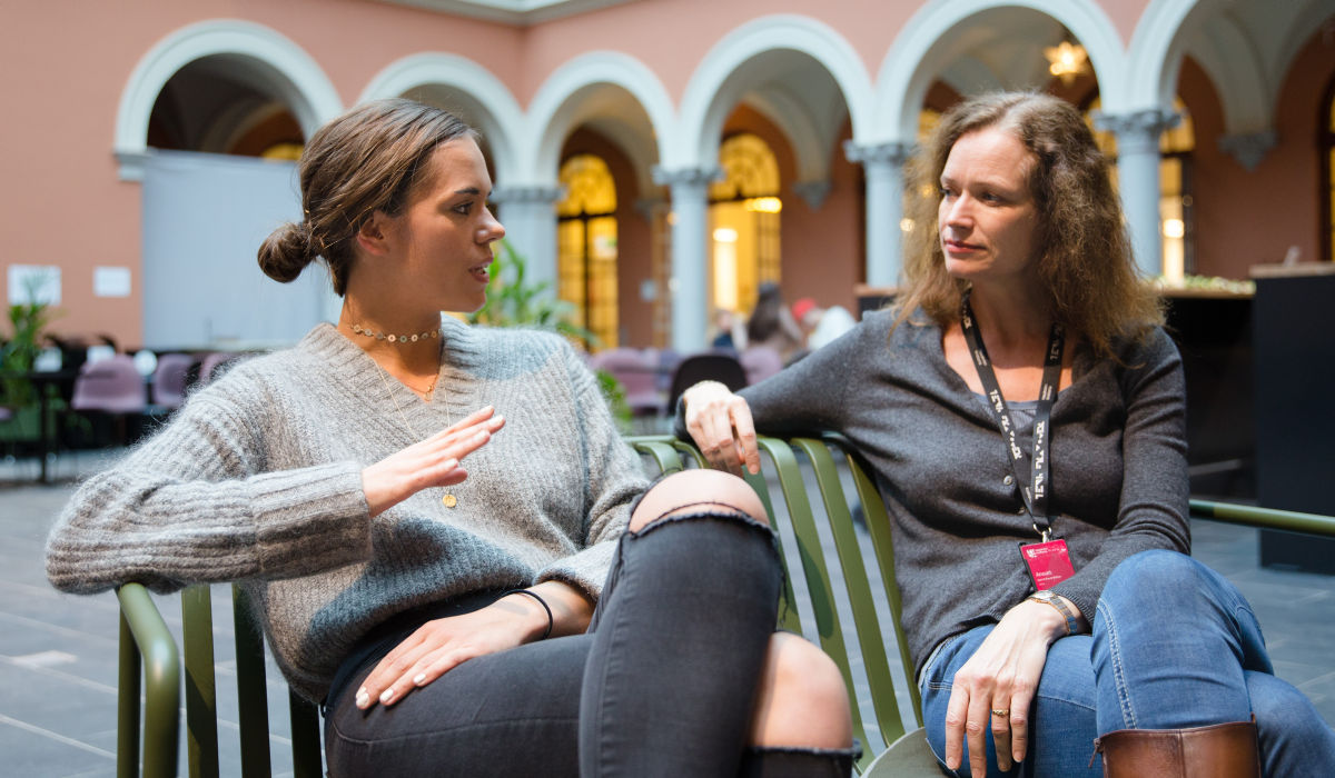 Kjersti Ruud Walaas sitter sammen med en student og prater.