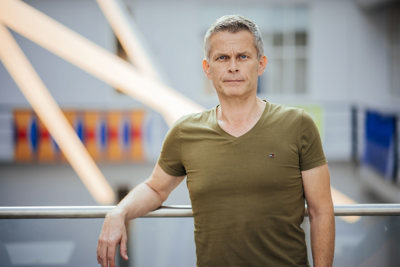 Mann i grønn t-skjorte lener seg på et rekkverk.