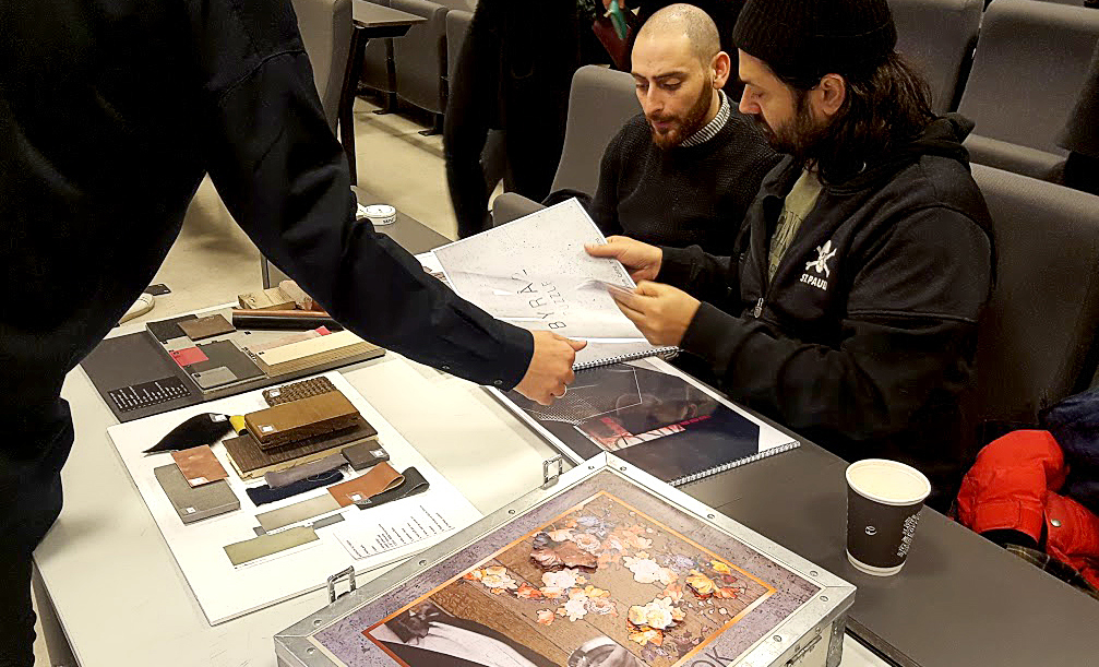 Himkok-ansatte sitter i et auditorium og gjennomgår mapper med studentenes designløsninger.