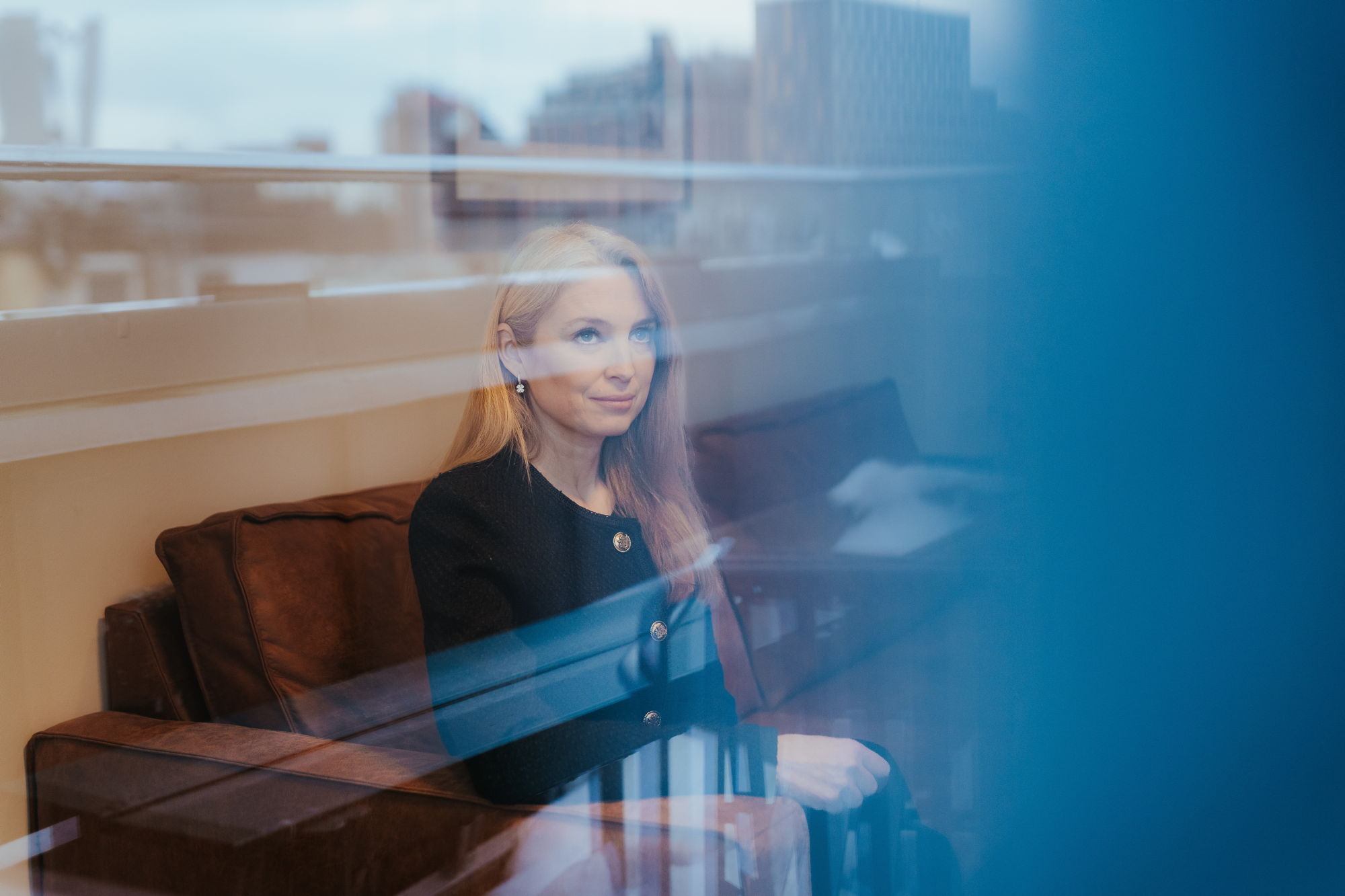 Helene Tronstad Moe sitter i en sofa og ser ut gjennom et vindu.