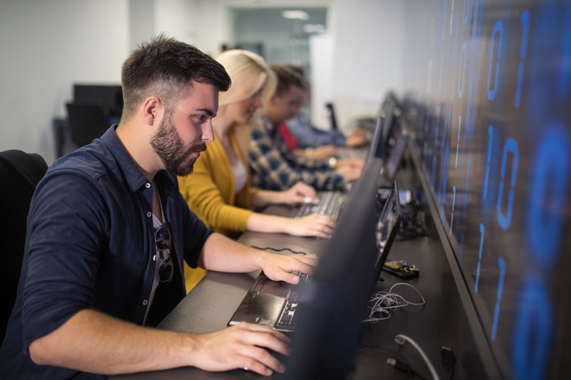 mann som sitter foran en stasjonær PC i en datalab på Kristiania