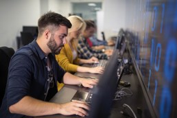 mann som sitter foran en stasjonær PC i en datalab på Kristiania