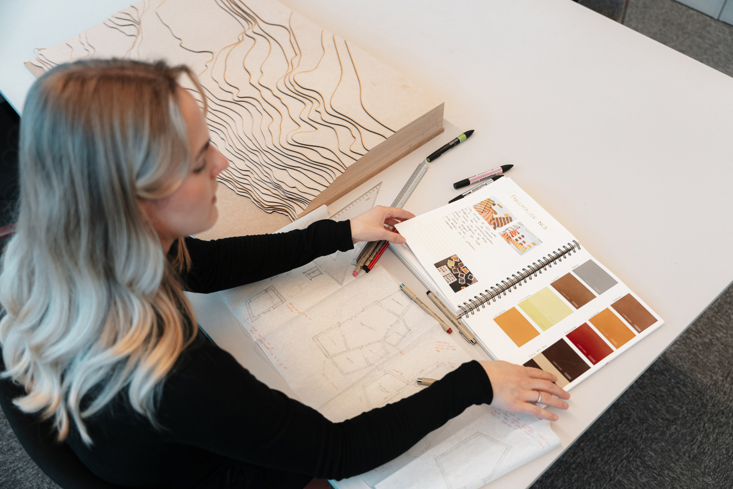 Foto av Master i design-student med designbøker.