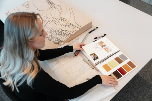Foto av Master i design-student med designbøker.
