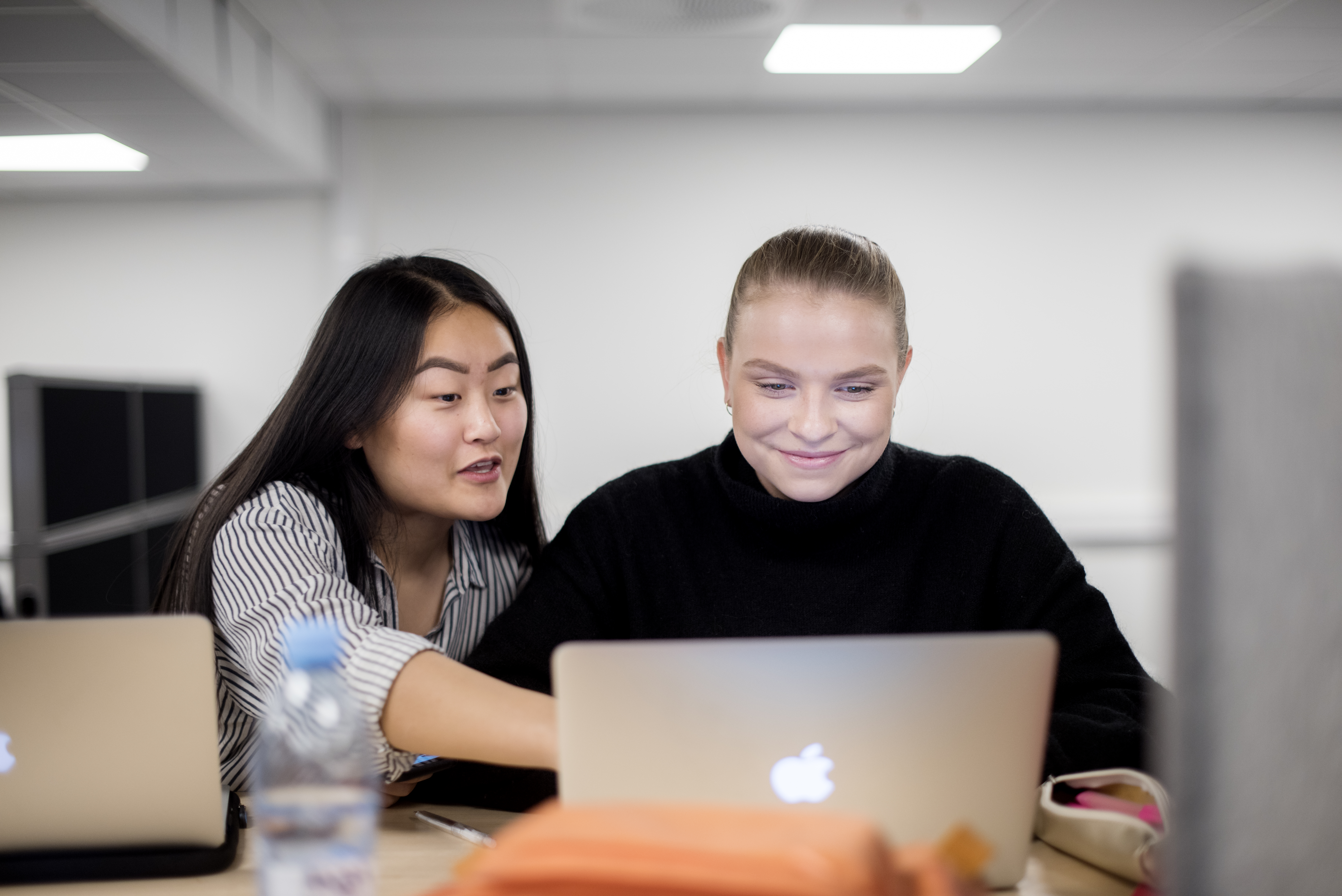 Foto av to kvinnelige studenter som jobber med en PC.