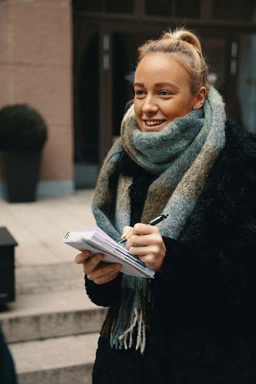 Ung journalistikkstudent med en notatblokk og pen i hendene. 
