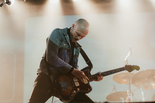 Gitarist spiller på sene foran et slagverk.