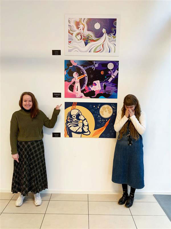 To unge kvinner peker på samme bilde av en kvinnelig astronaut.