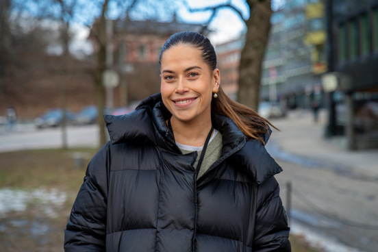 Portrett av Madelen som står utendørs og smiler. 