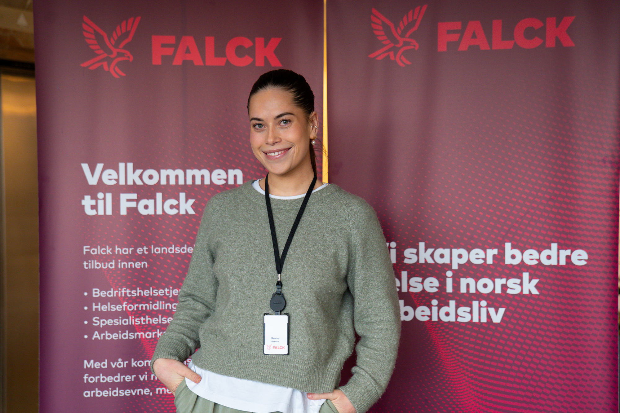 Madelen står foran en roll-up med Falck sin logo og smiler mot kameraet.