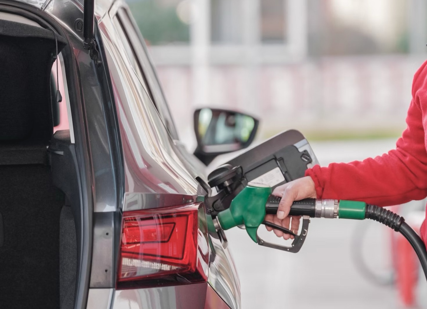 En person som fyller bensin i bilen på bensinstasjonen