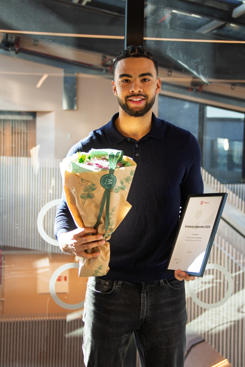 Student Adam Halås med diplom og blomster i forbindelse med at fikk Ernst G.-stipend på Høyskolen Kristiania i 2024.