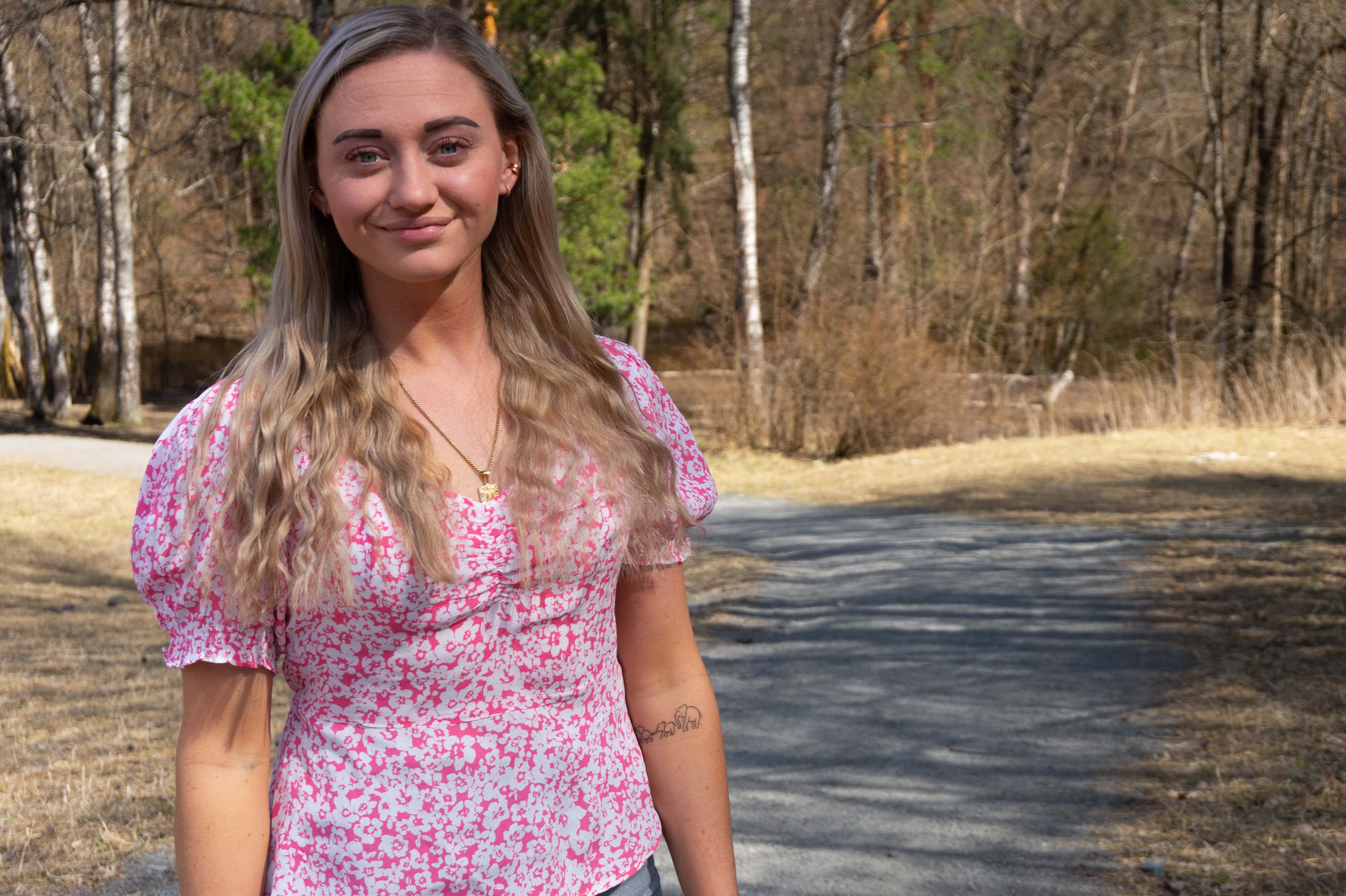Ung blond kvinne i blomstrete kjole i skogslandskap