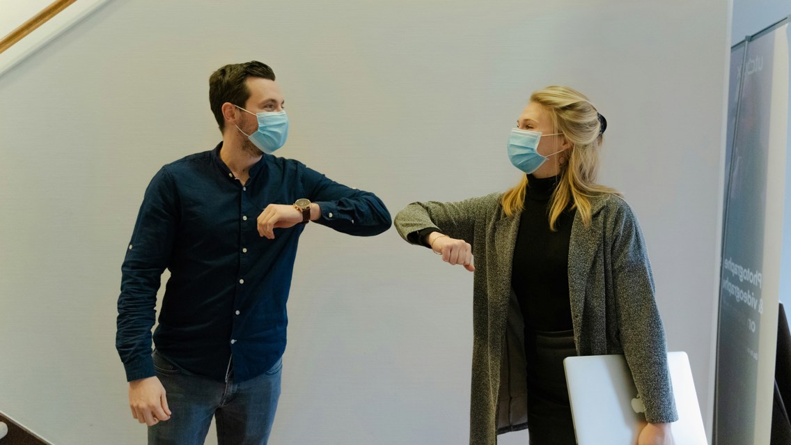 Woman and man greeting wearing face masks during covid-19 pandemic