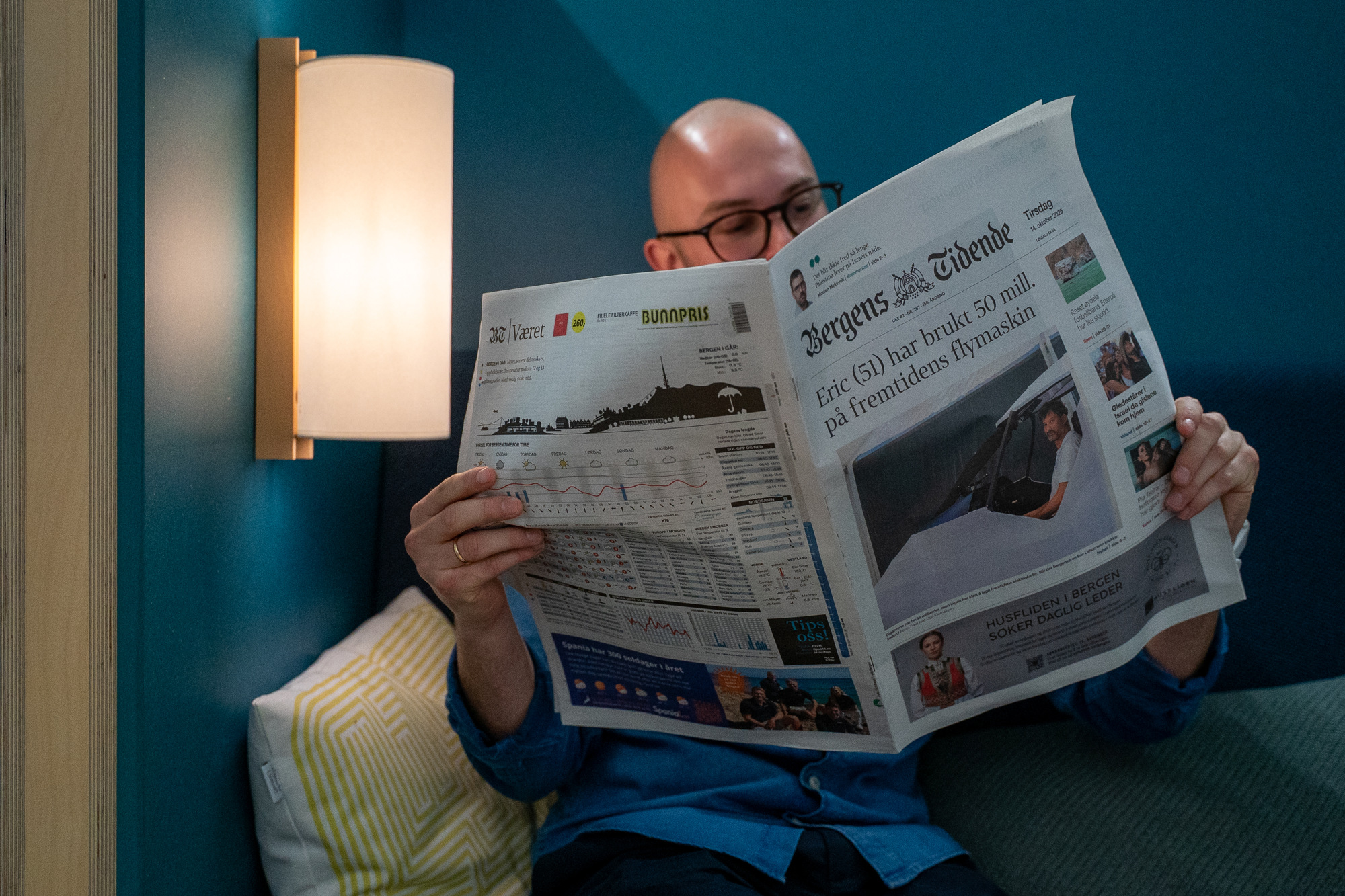 Isac leser Bergens Tidende i et lesehjørne på kontoret.