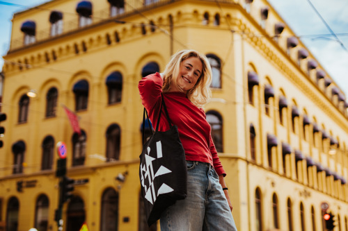 Student med Kristiania-totebag utenfor murbygg i Kvadraturen, Oslo.