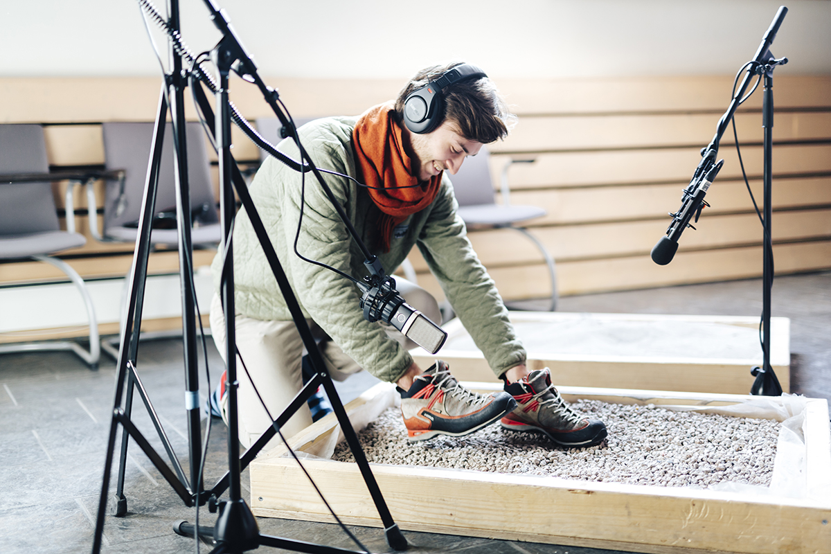 Student lager lyder med sko på grus i Foley-studio.