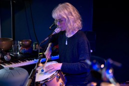 Kvinnelig musiker på scenen ved en mikrofon og trommer
