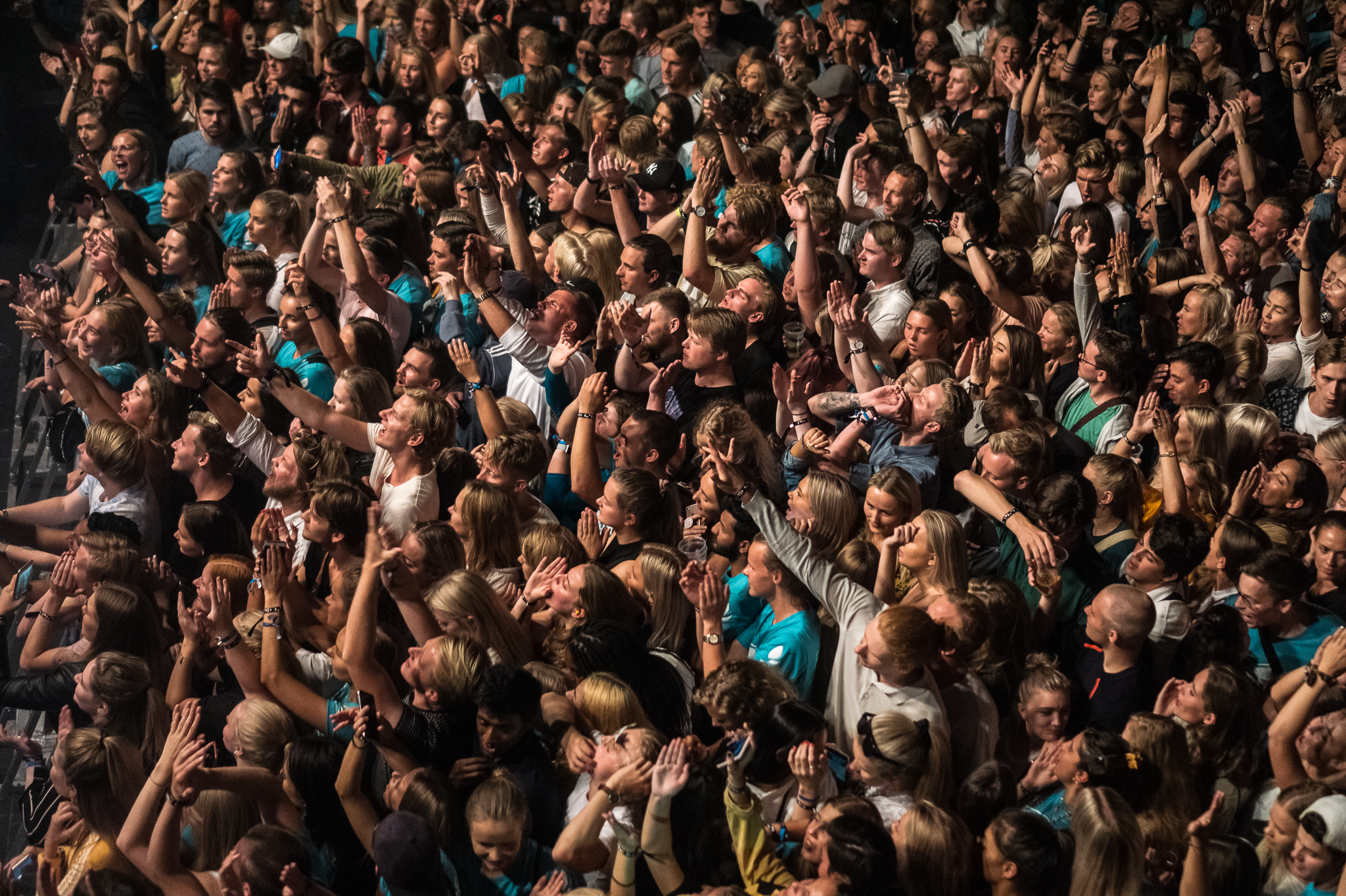 En folkemengde på konsert strekker armene i lufta.