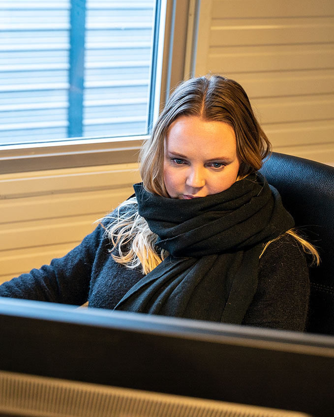 Agnete Matre sitter og ser på skjermen der hun jobber med alt fra kundeservice til grafisk design.