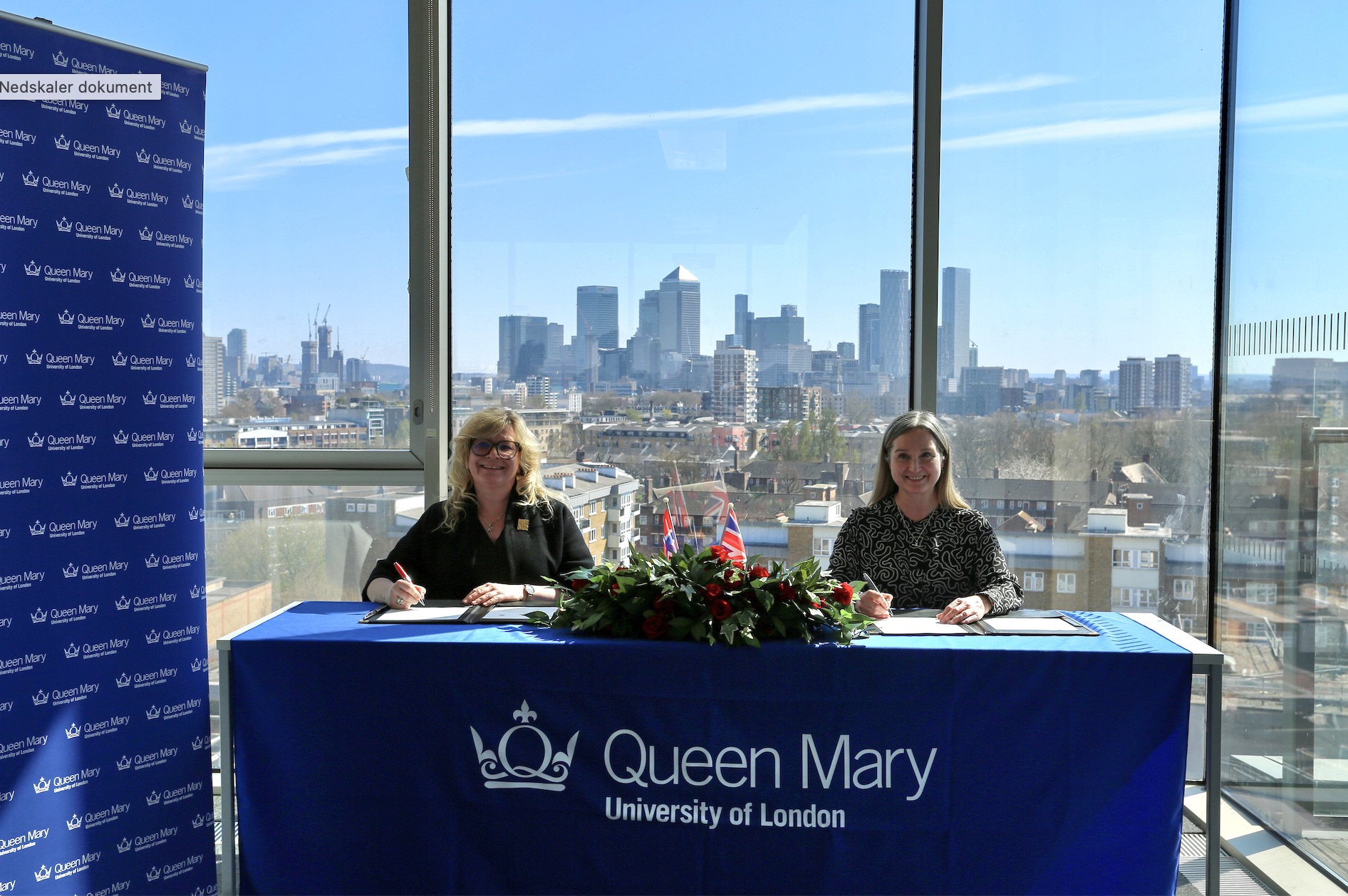 Signerer avtale foran et stort vindu på Queen Mary University London