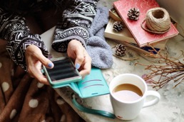 Woman sitting at a table with her phone and a cup of tea