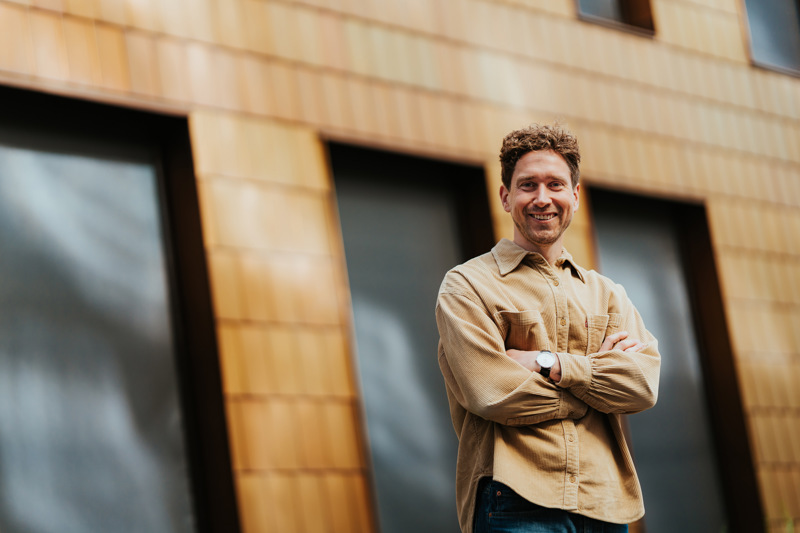 Mann står foran kontorbygg med armene i kors.