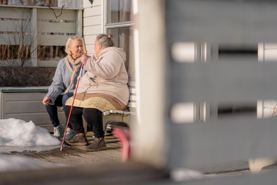To personer sitter på en benk og har en samtale