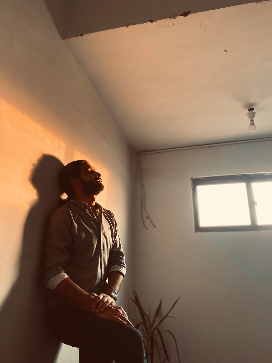 A man standing against the wall in lighting from the windows