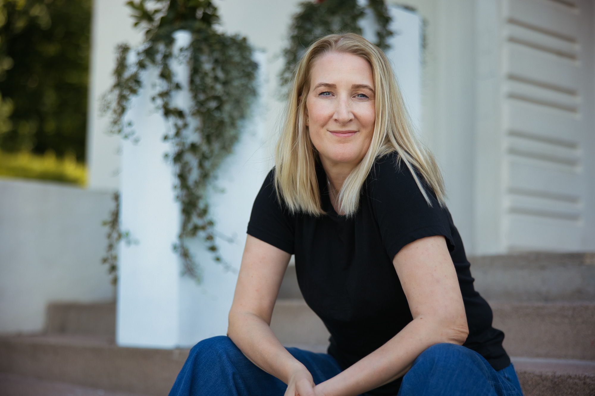 Christine sitter på en trapp utenfor et hvitt hus.