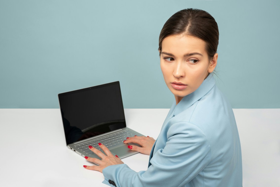 Kvinne med laptop ser seg over skulderen