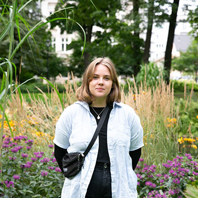 Kristiania-studenten Pauline Østgård fotografert i en park med mange blomster