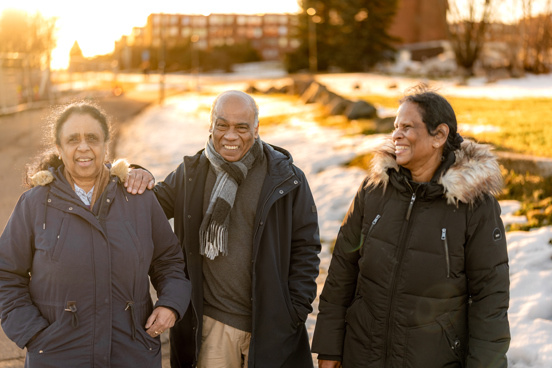 Tre personer går bortover en vei mens de smiler