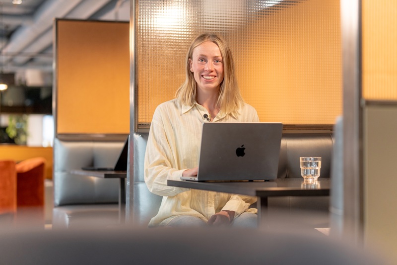 Person jobber på bærbar PC ved bord i moderne, lyst kontormiljø 