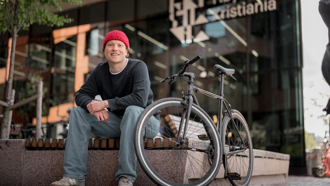 Person sitter med sykkel utenfor Kristiania campus