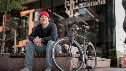 Person sitter med sykkel utenfor Kristiania campus