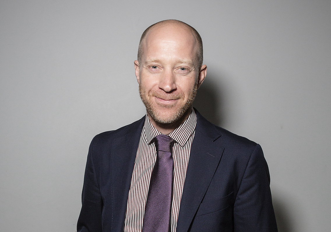 The picture shows Nigel Halpern in a suit and tie, smiling. 