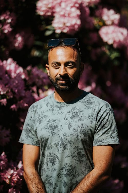 Juned står foran en stor rhododendron som blomstrer.