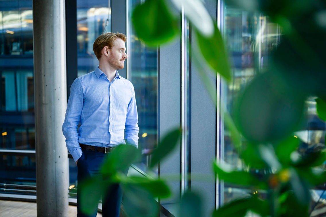 Ung mann i skjorte ser ut vinduet på et kontor 