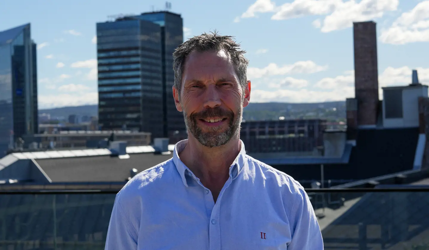 Professor Tom Karp står på taket av Kristianias nybygg, med en vakker utsikt over Oslo i bakgrunnen