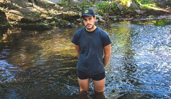 Foto av person som står i en elv, i underbuksa.