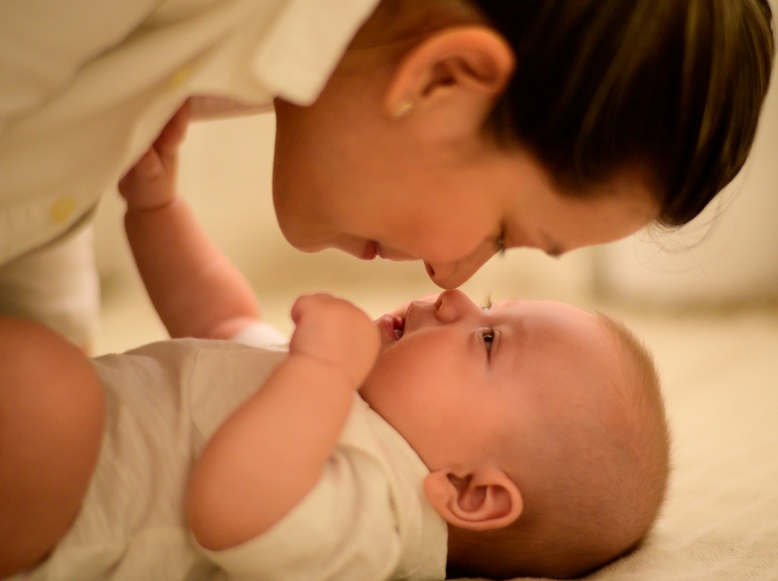 A woman touches nose with her small baby