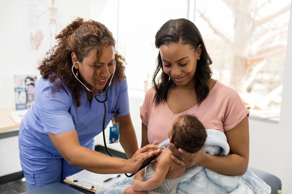 A female doctor is listening to the heart of a new born baby