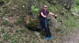 En mann lener seg mot en stor stein i skogen 